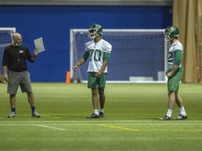 Saskatchewan Roughriders head coach Craig Dickenson  (left) works with Global punters Kaare Vedvik (70) and Ben Scruton (72) during a recent practice.