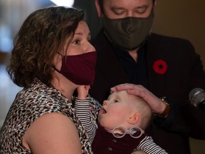 Graham Dickson and Laura Weins, shown holding their baby Helen, speak to media in the rotunda at the Saskatchewan Legislative Building on Nov. 3, 2021. Baby Helen's potential cerebral palsy diagnosis has been put on hold brought about by service slowdown as a result of COVID-19.