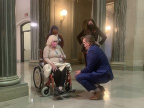 Premier Scott Moe on Nov. 4, 2021 listens in the legislature's rotunda to 70-year-old Dallas Oberik explaining her struggles to get hip replacement surgery.