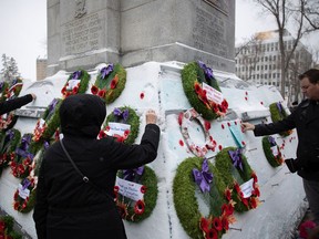 People pin poppies on the cenotaph following a Remembrance Day ceremony in Victoria Park in Regina on Nov. 11, 2021.