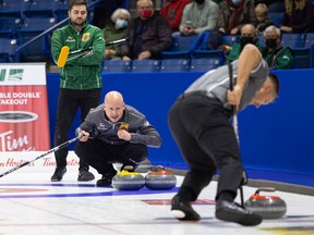 Ben Hebert sweeps, as Kevin Koe calls the shot and Matt Dunstone keeps an eye on things during Monday's Canadian Olympic curling trials.