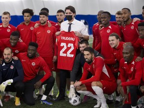 The Canadian mens national soccer team poses for a picture with Prime Minister Justin Trudeau during a practice at the Edmonton Soccer dome on Monday, Nov. 15, 2021 in Edmonton.