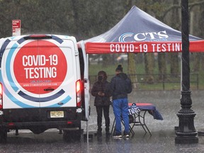People stand under a tent at a COVID-19 testing station during an autumn Nor'easter on October 26, 2021 in the Brooklyn borough of New York City.
