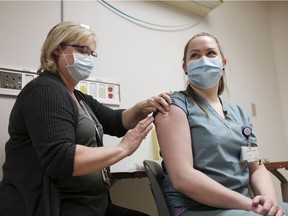Debbie Frier, registered nurse, left, injects Leah Sawatsky, an emergency room nurse, right, with the Pfizer-BioNTech COVID-19 vaccine at the Regina General Hospital in Regina on Tuesday, Dec. 15, 2020.