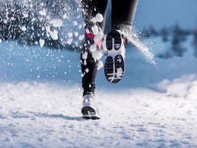 Athlete woman is running during winter training outside in cold snow weather.