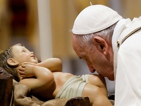 Pope Francis kisses a statue of baby Jesus as he celebrates Christmas Eve Holy Mass in St. Peter's Basilica at the Vatican, December 24, 2021.