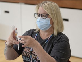 Public health nurse Joy Haroldson prepares a syringe of Pfizer COVID-19 vaccine at the mâmawêyatitân centre in Regina, Saskatchewan on May 31, 2021.