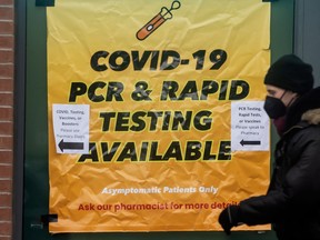 A pedestrian walks past signs advertising COVID testing on Toronto’s Queen Street.