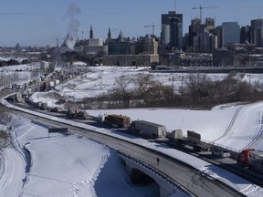 In this photo taken using a drone, vehicles of the protest convoy are seen parked on the Sir John A. Macdonald parkway leading in to downtown Ottawa, Sunday, Jan. 30, 2022. Residents of the national capital are again being told to avoid travelling downtown as a convoy of trucks and cars snarl traffic protesting government-imposed vaccine mandates and COVID-19 restrictions.