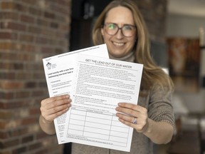 Heather Dedman, member of the Cathedral and Area Community Association's Get The Lead Out Committee, holds up a petition on Tuesday, February 22, 2022 in Regina.