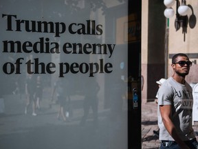 A man, shown in Helsinki in 2018, walks past an advertising board reading "Trump calls media enemy of the people."