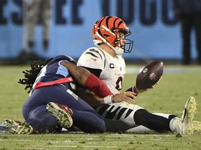 The Cincinnati Bengals' Joe Burrow, right, reacts after being sacked by the Tennessee Titans' Bud Dupree on Jan. 22 during an NFL divisional playoff game. Cincinnati won 19-16 even though Burrow — who is to quarterback the Bengals in Sunday's Super  Bowl against the Los Angeles Rams — was sacked nine times.