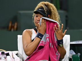 Naomi Osaka wipes her face as she talks to referee Claire Wood after a spectator disrupted play, yelling “Naomi you suck,” before the start of her 2nd round match against Veronika Kudermetova at the BNP Paribas open at the Indian Wells Tennis Garden in Indian Wells, Calif., March 12, 2022.