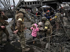 TOPSHOT - People cross a destroyed bridge as they evacuate the city of Irpin, northwest of Kyiv, during heavy shelling and bombing on March 5, 2022, 10 days after Russia launched a military invasion on Ukraine.