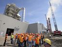 A tour group looks at the carbon capture building, left, that is currently under construction at Boundary Dam Power Station in Estevan, Sask. on Wednesday, May 22, 2013.