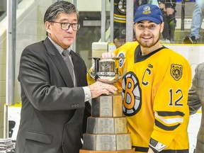 Estevan Bruins captain Eric Houk (right) accepts the 2022 SJHL championship trophy from league president Bill Chow.