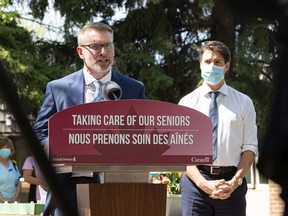 Prime Minister Justin Trudeau, right, looks on as Saskatchewan Minister of Mental Health and Addictions, Seniors, and Rural and Remote Health Everett Hindley speaks during a media event at St. Ann's Senior Citizens' Village in Saskatoon on May 25, 2022.