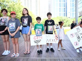 Protesters hold photos of victims of the Robb Elementary School shooting outside the National Rifle Association annual meeting at the George R. Brown Convention Center, on May 27, 2022, in Houston, Tex. America's powerful National Rifle Association kicked off a major convention in Houston Friday, days after the horrific massacre of children at a Texas elementary school.