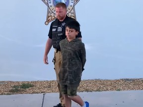 Boy, 10, handcuffed being led away by police officer.