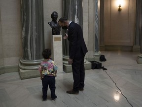 Out-going NDP leader Ryan Meili and his son Gus examine the Tommy Douglas bust in the legislature's rotunda.