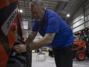 Lang Neufeldt from Superior Forklift ltd. cleans a skid steer before Canada's Farm Show inside the REAL District/Exhibition Grounds on Monday, June 20, 2022 in Regina.