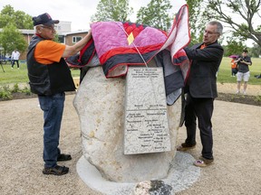 Elder Ted Quewezance, left, residential school survivor from Keeseekoose First Nation, and Lt.-Gov. Russ Mirasty unveil the the large stone at the centre of the Saskatchewan Residential School Monument, which was chosen by Mirasty and relocated from the Qu'Appelle Valley.