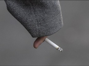 A pedestrian walks across Bloor Street while holding a lit cigarette in Toronto, Dec. 2019.
