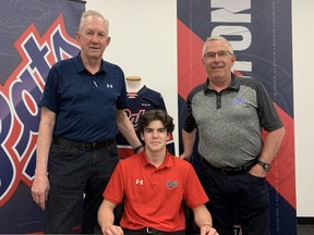 Cole Temple, centre, is shown signing a standard WHL player agreement with the Regina Pats. Also shown are head coach and general manager John Paddock, left, and director of scouting Dale McMullin.