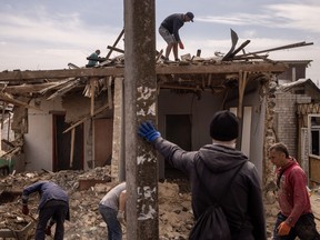 Residents clear debris from a damaged house after the residential area was hit by a Russian attack on April 29, 2022 in Zaporizhia, Ukraine.