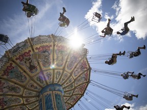 Attendees ride on a swing ride during the Queen City Ex at the REAL District on Wednesday, August 3, 2022 in Regina.