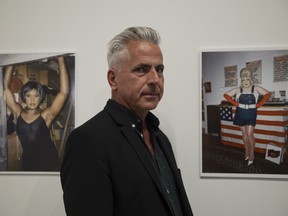 Guest curator Gary Varro stands in front of photographs by Linda Simpson during the opening reception of The Drag Explosion at the Art Gallery of Regina on Thursday, Aug. 11, 2022 in Regina.