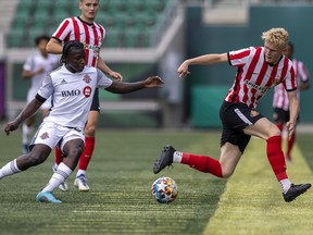 Toronto FC II's Nakye Greenidge-Duncan, left, and Sunderland AFC's Ben Crompton chase a loose ball Wednesday night at Mosaic Stadium.