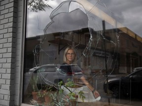 Takeaway Gourmet manager Jillian Warawa sits for a portrait at the local business next to a pane of broken glass.