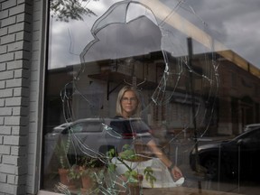 Takeaway Gourmet manager Jillian Warva sits next to a pane of broken glass for a portrait at the local business.