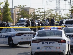 Police vehicles and officers are seen behind tape at a scene in Mississauga, Ont., Monday, Sept. 12, 2022. Shootings across the Greater Toronto Area left two people dead, including a Toronto police officer, and injured three others on Monday afternoon.