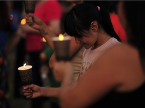 A child holds a candle at at a vigil held for the victims of a mass killing in and near James Smith Cree Nation, which was held at the First Nations University of Canada in Regina on Sept. 7, 2022