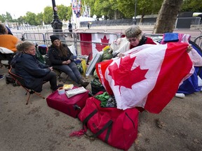 Bernadette Christie, of Grand Prairie, Alta., looks for a Canadian pin on a flag at the gates of Buckingham Palace in London, Friday, Sept. 16, 2022.&ampnbsp;For some Canadians, Queen Elizabeth's funeral today will evoke a range of emotions while for others it is a distant event that they are likely to miss.&ampnbsp;THE CANADIAN PRESS/Nathan Denette