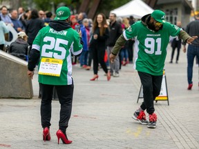 Saskatchewan Roughriders running back Jamal Morrow, left, and defensive lineman Anthony Lanier II take part in the 7th Annual Walk A Mile in Their Shoes fundraising event where people walk in red high heels around Victoria Park.