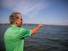 Rick Vigrass points to Katepwa lake while standing on his dock.