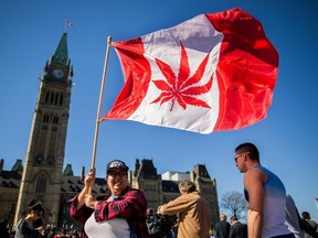 This file photo taken on April 20, 2016 shows a woman waving a flag with a marijuana leaf on it next to a group gathered to celebrate National Marijuana Day on Parliament Hill in Ottawa, Canada.