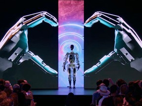 This video screen grab made from Tesla AI Day 2022 livestream shows Elon Musk (L) presenting the humanoid robot in Palo Alto, California on September 30, 2022.