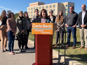 NDP Leader Carla Beck stands in front of her caucus in Prince Albert on Wednesday, announcing a shuffling of roles.