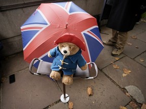A Paddington bear stuffed toy is placed on a chair next to a Union flag umbrella as people wait opposite the Palace of Westminster to be first in line bidding farewell to Queen Elizabeth II in London on Sept. 14, 2022.