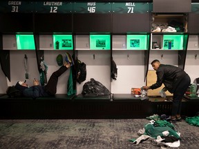 Saskatchewan Roughriders kicker Brett Lauther (left) rests on a bench as catcher Shaq Evans cleans out his locker during Sunday's trash bag day.