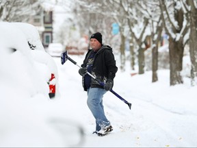 A resident cleans a vehicle on the street during a snowstorm as extreme winter weather hits Buffalo, New York November 18, 2022.