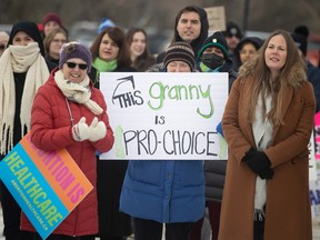 Supporters hold up signs during a solidarity protest and call to action is a protest being held at the Legislative Building.