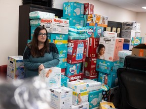 Development coordinator Aurora Marinari for Carmichael Outreach stands for a portrait beside a heap of donations on Monday, December 19, 2022 in Regina.