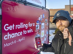 Jeremy McDougall of Tillsonburg shows what he thinks of Tim Hortons on Thursday, March 9, 2023, after the chain denied his prize of $10,000, offering him a $50 gift certificate instead. McDougall said he was congratulated by Tim Hortons managers for winning $10,000, as his phone showed, before he was told it was a mistake. (Mike Hensen/The London Free Press)
