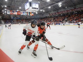 Team Canada forward Sarah Nurse (left) and Japan defender Ayaka Hitosato (right) chase a puck into the corner during first period IIHF Women's World Hockey Championship action in Brampton, Ont., Saturday, April 5, 2023.