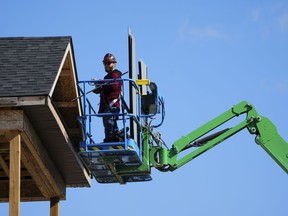 A construction worker works from a lift in a new housing development in Ottawa on Friday, Oct. 14, 2022. An Indigenous-owned investment firm is partnering with the Canada Mortgage and Housing Corporation to build several hundred homes for Indigenous communities.